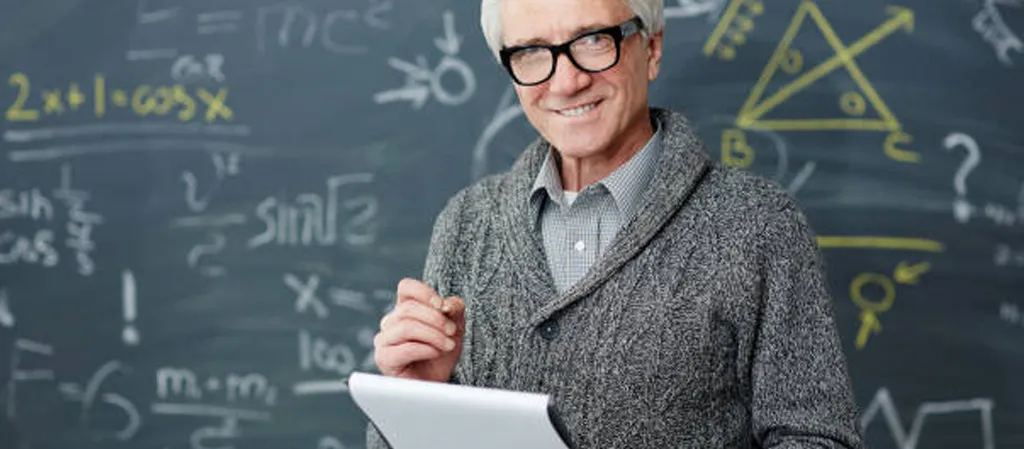 Teacher smiling and standing in front of a chalkboard.